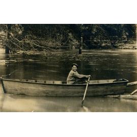 Bill Letty in a rowboat on a flooded creek