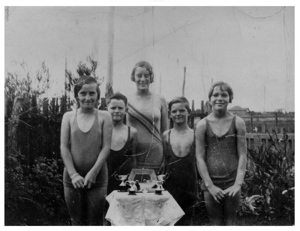 Five young swimmers with trophies