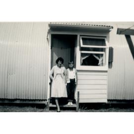 Peggy Pearson and son standing in the doorway of a Nissen Hut, Cabramatta Migrant Hostel, Cabramatta NSW