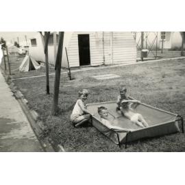 Four children playing in a pool in the drying area, Cabramatta Migrant Hostel, Cabramatta NSW