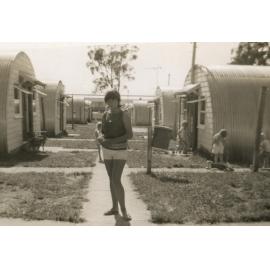 A girl is standing on a path between the Nissen huts, Cabramatta Migrant Hostel, Cabramatta NSW