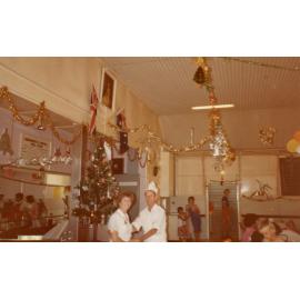 A man and a woman standing under ceiling decorations, Cabramatta Migrant Hostel, Cabramatta NSW