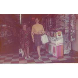 Two women walking out of a shop.