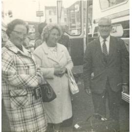 Three adults standing near a bus