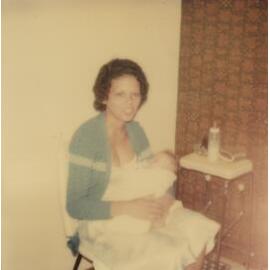 A seated woman holding a baby.